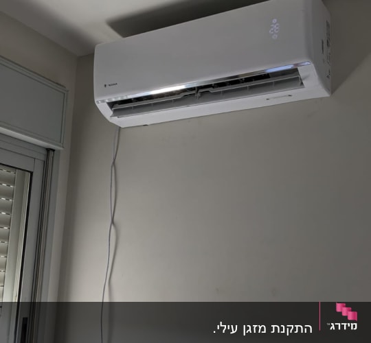 מזגן מותקן על קיר עם כבל חשמל מחובר